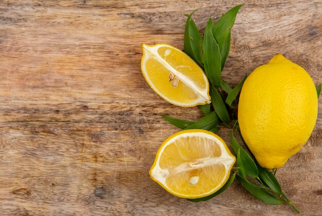 Top view of yellow lemon with tarragon green on a wooden surface