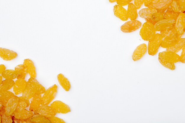 Top view of yellow raisins heaps on white background with copy space