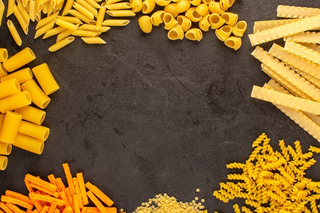 Вид сверху желтые сырые макароны разные сформированные изолированные мало и долго на темном фоне еда еда спагетти Италия