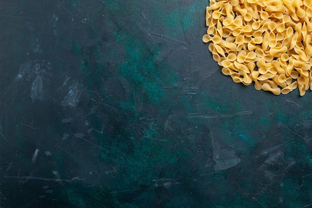 Free photo top view yellow raw pasta italian pasta on the dark-blue desk