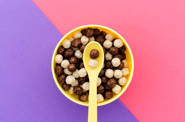 Top view yellow spoon with bowl of chocolate cereals