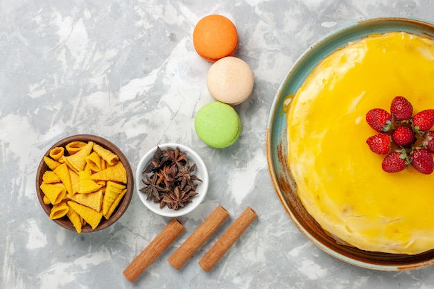 Free photo top view yellow syrup cake with french macarons on white background