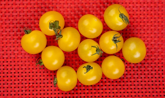 Free photo top view of yellow tomatoes on red cloth table