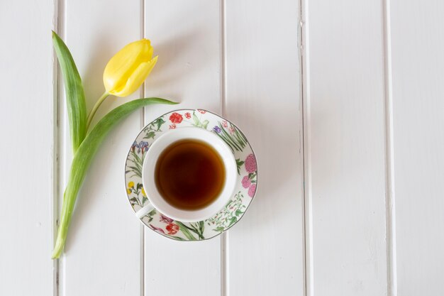 Top view of yellow tulip with cup of tea