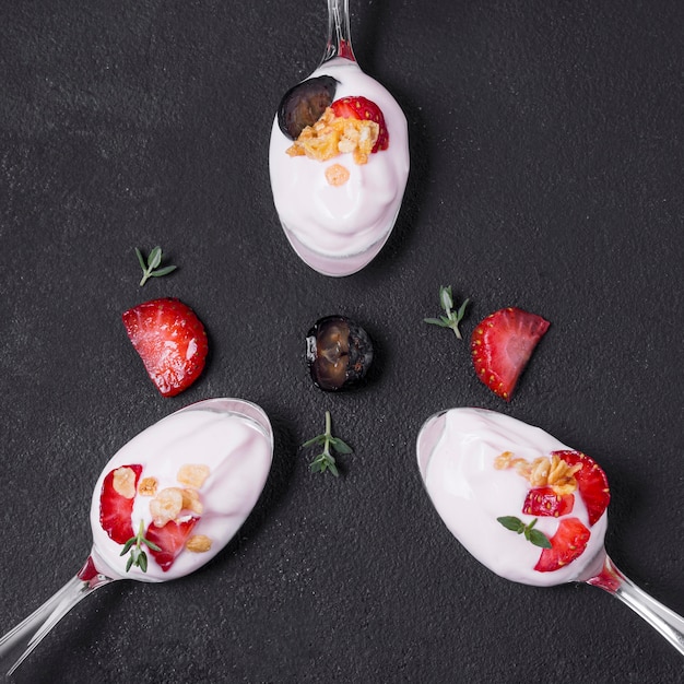 Free photo top view yogurt spoons with strawberries