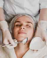 Free photo top view of young beautiful woman getting a face skin treatment