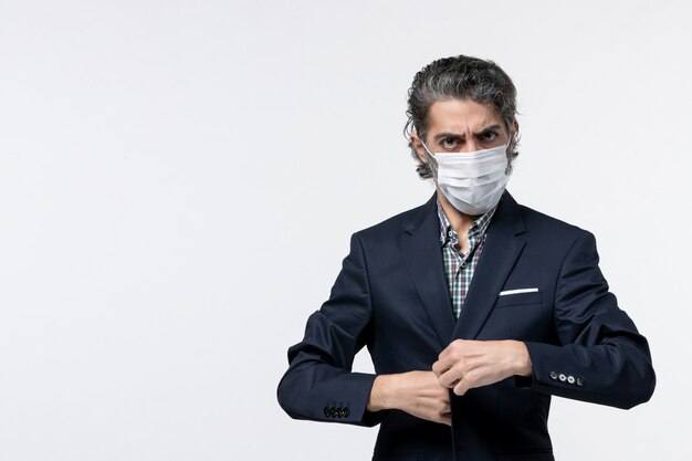 Top view of young businessman in suit wearing mask and posing for camera on white surface