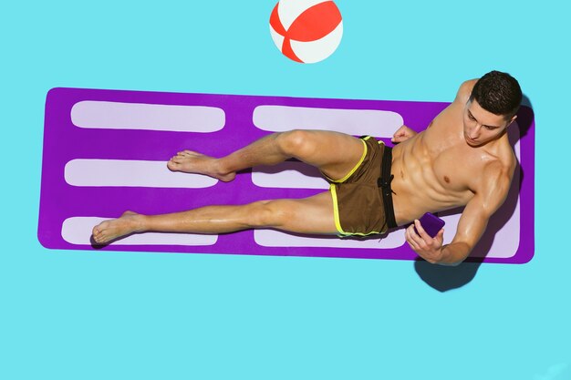 Top view of young caucasian male model's resting on beach resort on purple mat and blue