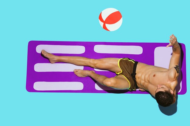 Top view of young caucasian male model's resting on beach resort on purple mat