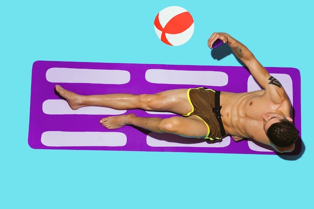 Top view of young caucasian male model's resting on beach resort on purple mat