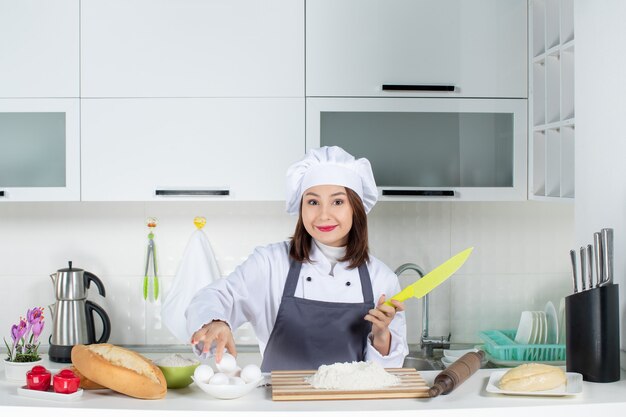 白いキッチンで料理を準備する制服を着た若い集中女性シェフの上面図