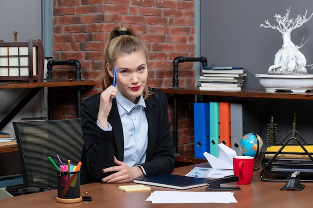 Vista dall'alto di una giovane assistente femminile sicura e determinata seduta alla sua scrivania in ufficio