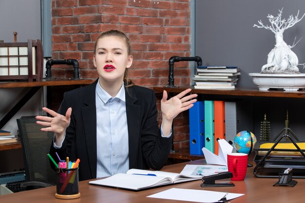 Вид сверху молодой женщины, сидящей за столом и нервничающей в офисе