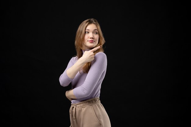 Top view of young girl pointing back something on dark