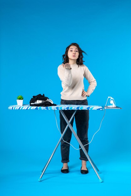 Top view of young girl standing behind the iron board making kiss gesture on blue wave surface