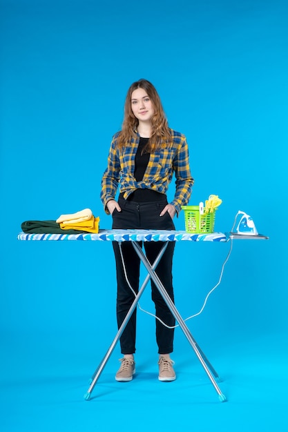 Top view of young girl standing behind the ironing board and posing