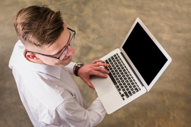 Top view of a young man using laptop holding in hand