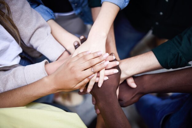 Top view of young people putting their hands together.