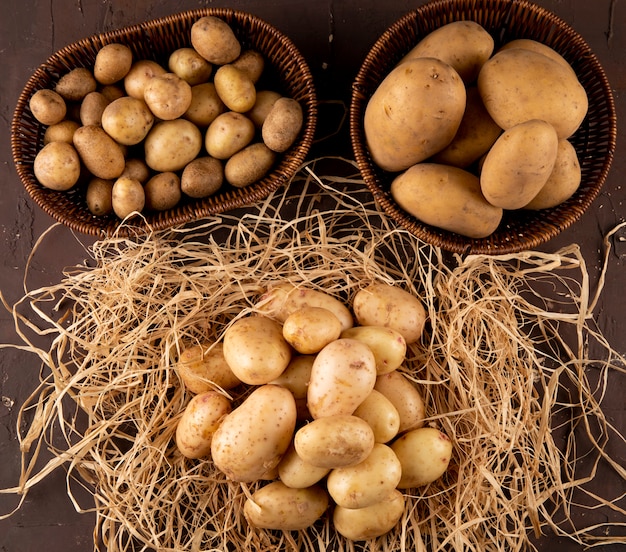 Вид сверху молодой картофель на сене с картофелем в корзинах