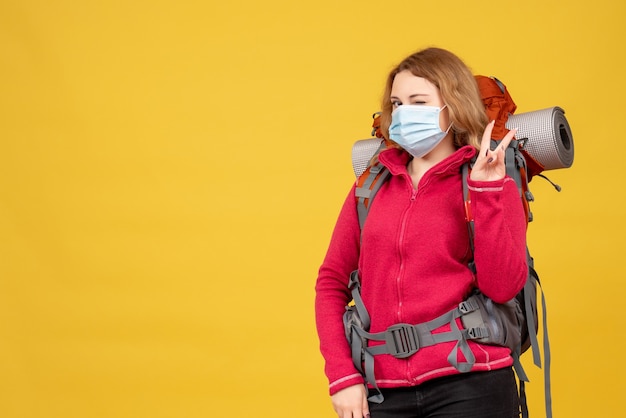 Top view of young travelling girl in medical mask collecting her luggage and making victory gesture