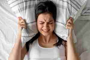 Free photo top view young woman holding pillow in bed