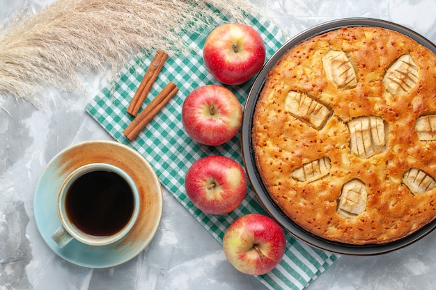 Вид сверху вкусный яблочный пирог, сладкий, запеченный на сковороде с чаем и яблоками на белом столе