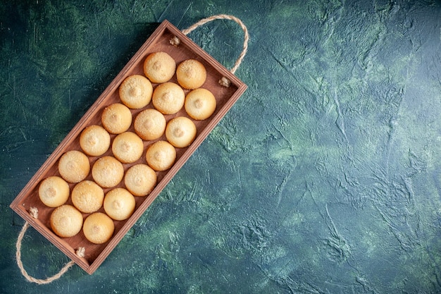 Вид сверху вкусное печенье внутри деревянной коробки на темно-синем фоне сахарное печенье бисквитный торт цвет сладкий ореховый чай свободное пространство