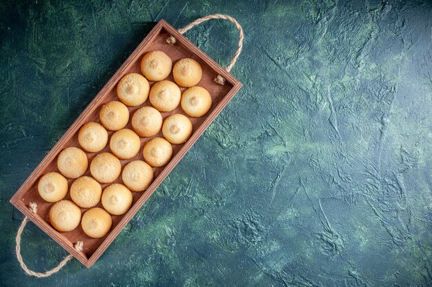 ダークブルーの背景に木製の箱の中のおいしいビスケットの上面図シュガークッキービスケットケーキパイ色甘いナッツ茶の空きスペース