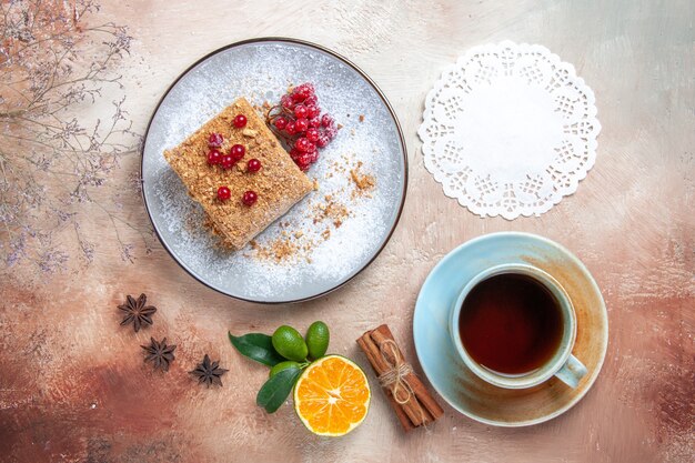 Top view yummy cake slice with tea and berries on a light