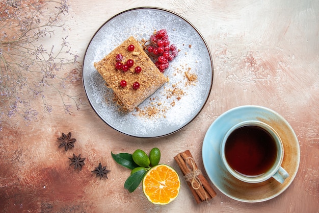 Free photo top view yummy cake slice with tea and berries on light