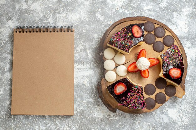 Top view yummy cake slices with choco cookies on white surface