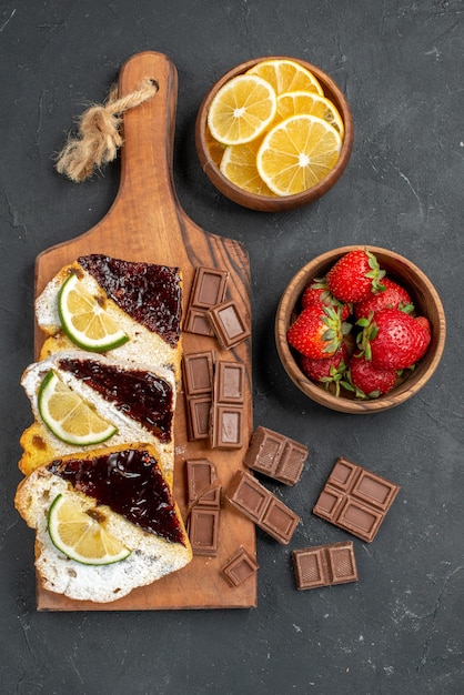 Top view yummy cake slices with chocolate and fruits on a dark surface