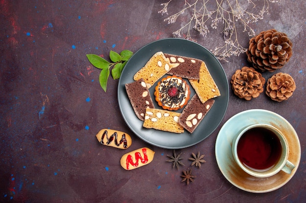 Free photo top view of yummy cake slices with cup of tea on black