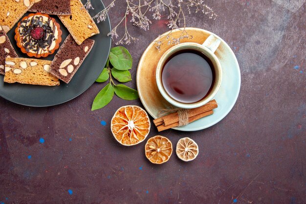 Top view of yummy cake slices with cup of tea on black