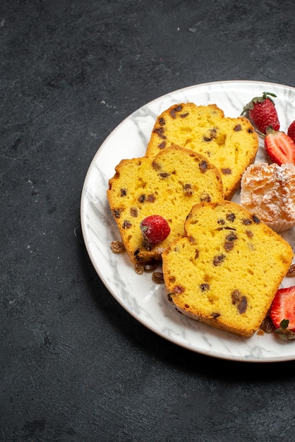 Vista dall'alto deliziose fette di torta con fragole rosse fresche e biscotti sulla superficie grigia