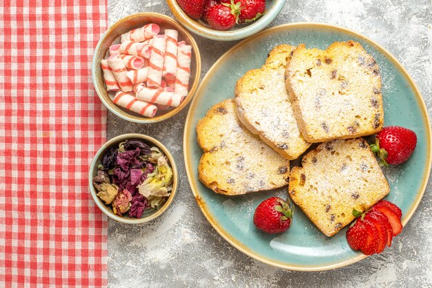 Вид сверху вкусные кусочки торта со свежей клубникой на белом