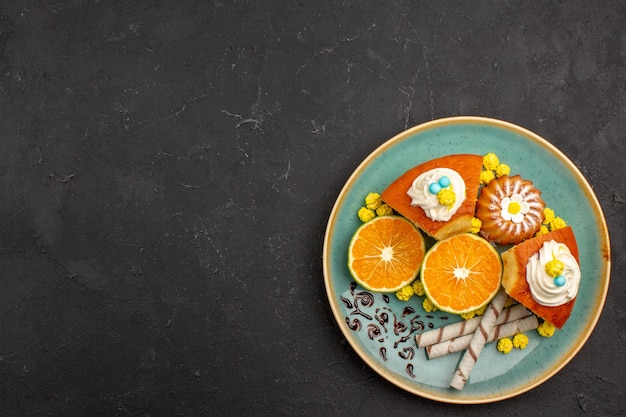 Top view yummy cake slices with pipe cookies and sliced tangerines on dark