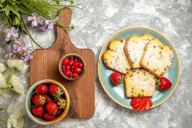 Вид сверху вкусные кусочки торта с клубникой на свете