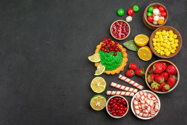 Top view yummy cake with candies and fruits on dark background cookie biscuit sweet free place