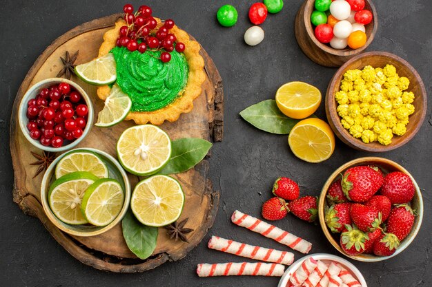 Top view yummy cake with candies and fruits on dark background cookie biscuit sweet