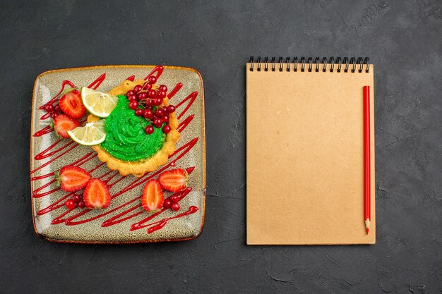 Top view yummy cake with green cream and strawberries on dark background dessert sweet tea