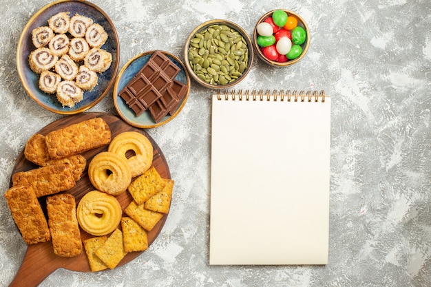 Top view yummy cakes with candies and cookies on the white background