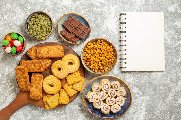 Top view yummy cakes with candies and cookies on white background