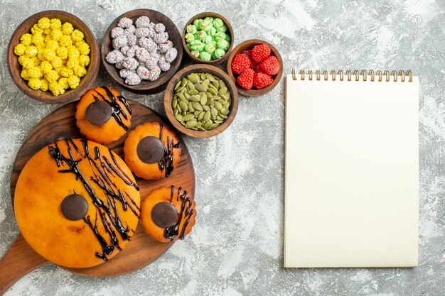 Вид сверху вкусные торты с шоколадной глазурью и конфетами на белой поверхности торт какао бисквитный пирог десертное сладкое печенье