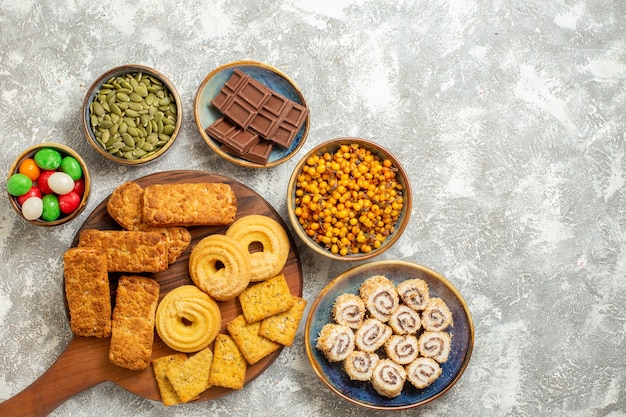 Top view yummy cakes with crackers and cookies on a white background