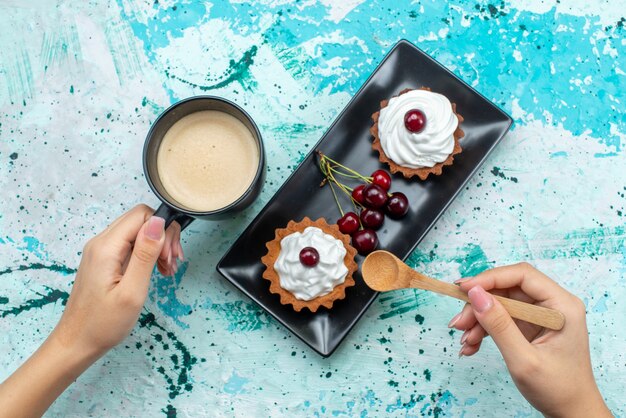 Top view yummy cakes with cream and fruits on the blue-light surface cake sweet cream bake fruit tea