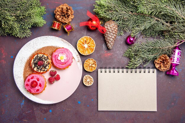 top view of yummy cakes with fruits and cream on black