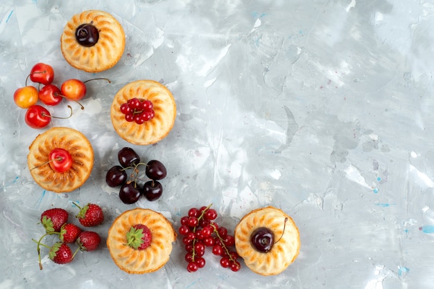 Вкусные торты с сочными и сочными красными фруктами на светлом письменном ягодном фруктовом торте, вид сверху