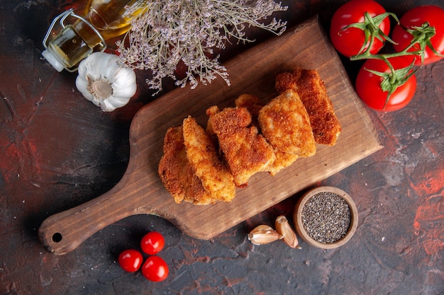 Top view yummy chicken wings on cutting board with tomatoes dark surface