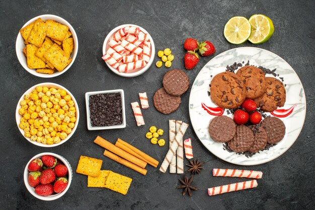 Top view yummy choco biscuits with different snacks on dark background tea sweet cookie